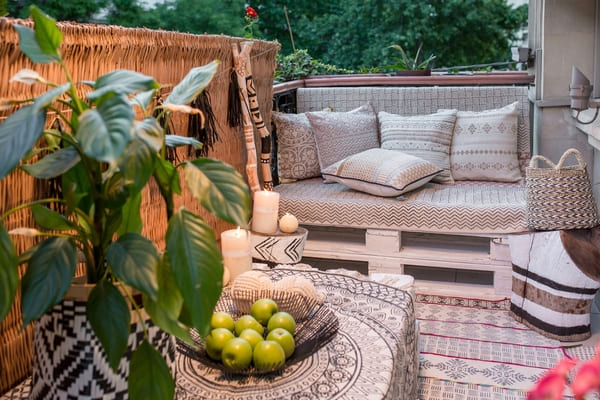 Sofá cerca de una mesa con velas y manzanas en el acogedor balcón